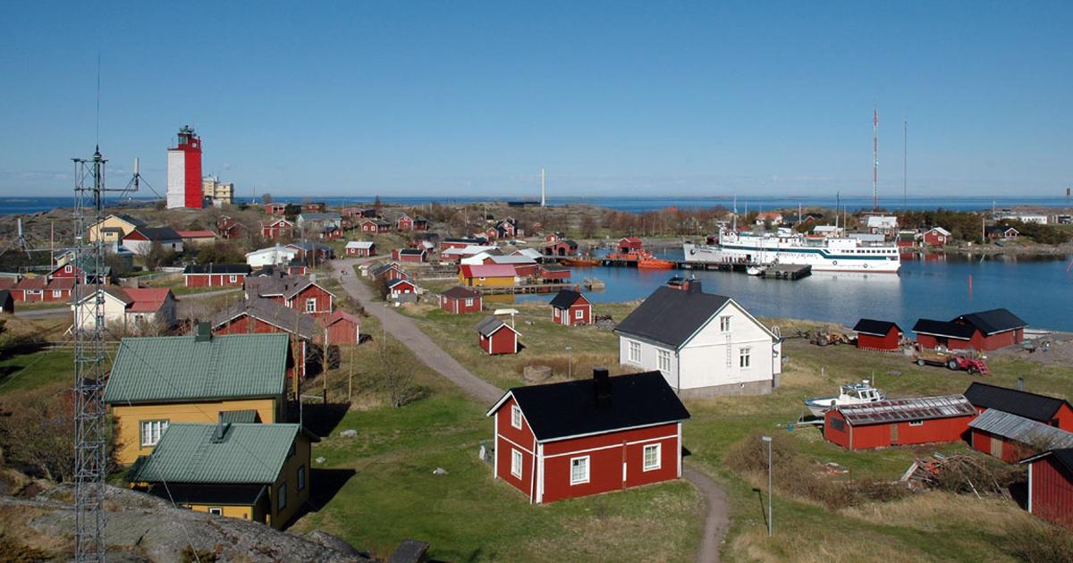 Kuva Ut&ouml;n saaren satama-alueesta ja taloista, taustalla majakka