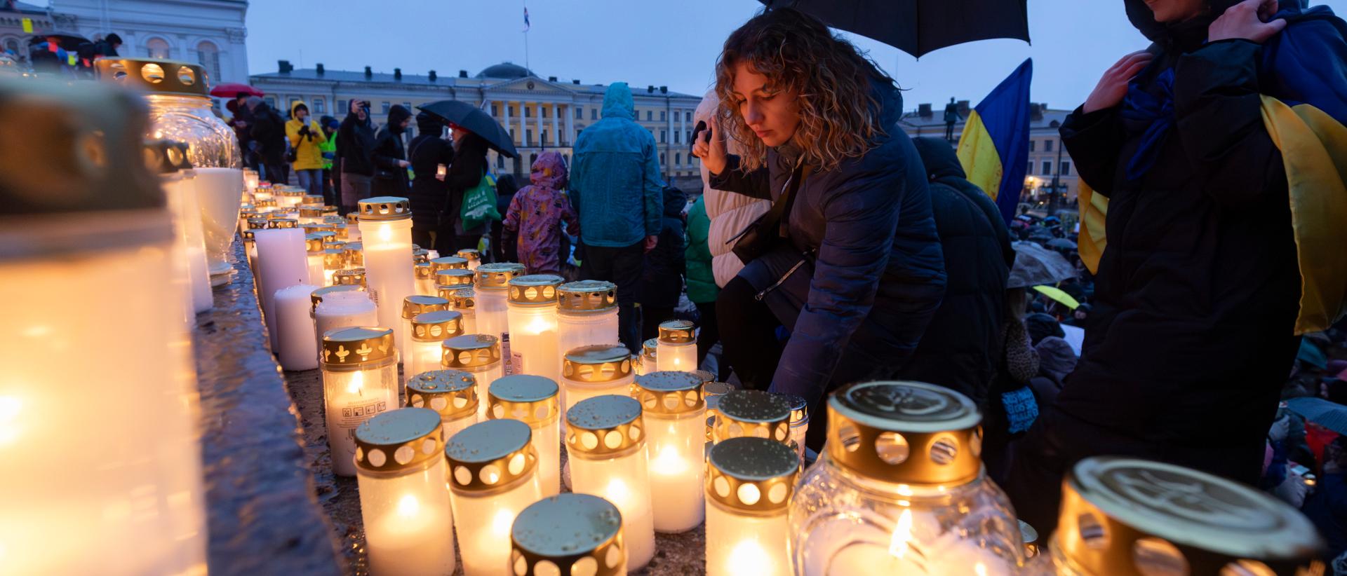 Nainen laskee kynttilän Tuomiokirkon portaille