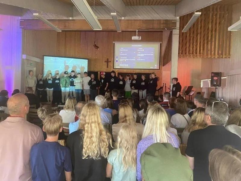 Bild från en besöksdag på Lekholmen. Konfirmanderna står på scen och familjerna tittar på.