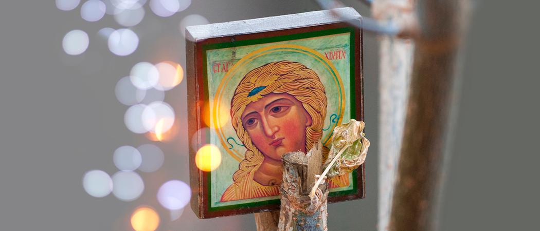 Harmaata taustaa vasten oksan varassa pieni Marian ikoni. Ympärillä valopisaroita.