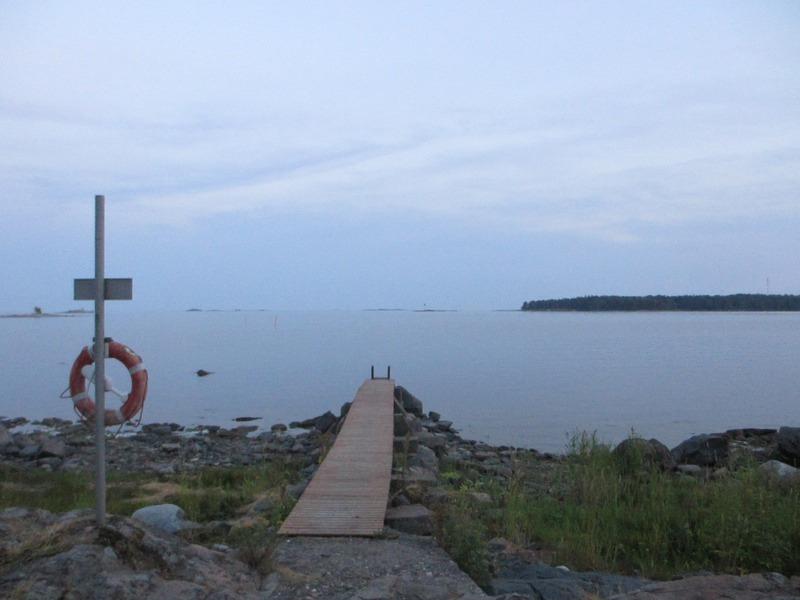 Lekholmens badbrygga i skumt ljus. Bredvid bryggan ser man en livboj.